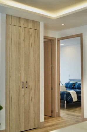 A bedroom with a wooden wardrobe, a bed with blue bedding, and a white wall. - Apartments in Cumbaya near Airport (Cumbayá)