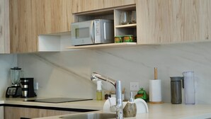 A modern kitchen with wooden cabinets, a built-in microwave, and a central island with a sink and bar stools. - Apartments in Cumbaya near Airport (Cumbayá)