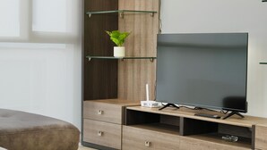 A modern living room with a flat-screen TV on a wooden TV stand, a small plant, and a remote control. - Apartments in Cumbaya near Airport (Cumbayá)