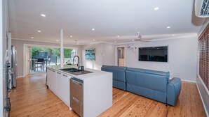 Una cocina moderna con una isla central, lavavajillas integrado y un comedor con mobiliario de exterior.