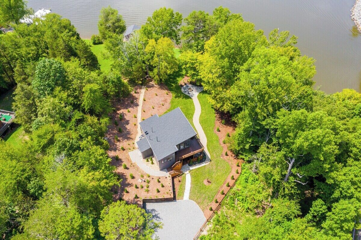 Una casa rodeada de árboles frondosos y un lago.
