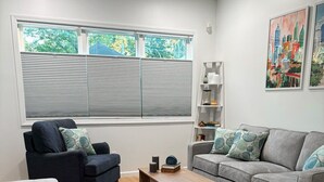 Ein modernes Wohnzimmer mit einem grauen Sofa, einem blauen Sessel, einem Holztisch und einem gemusterten Teppich.