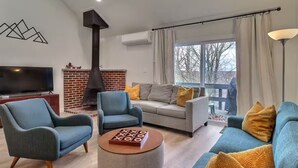 Ein Wohnzimmer mit Fernseher, zwei Sofas, einem Couchtisch und einem Kamin.