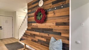 Eine Holzwand mit einer Uhr, einem Kranz, einer Bank und einer Treppe.