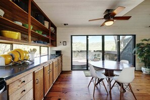 A kitchen with wooden cabinets, a dining table with chairs, and a ceiling fan.