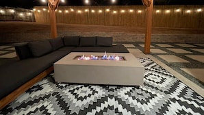Un espacio al aire libre acogedor con una chimenea, un sofá y un tapete estampado.