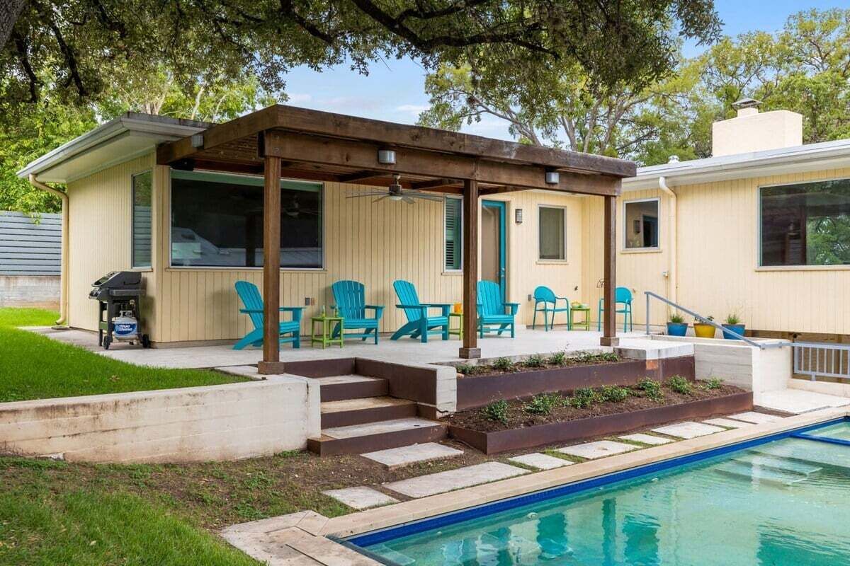 Un patio couvert avec des sièges d’extérieur, une piscine et un barbecue.