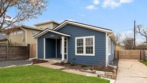 Una casa a un piano con facciata blu scuro, un portico e il numero 3003 sulla facciata.