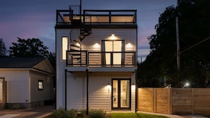 A two-story house with a balcony, a visible staircase, and a well-lit entrance. - 🎶 East Austin Retreat w/ Balcony + Backyard | Urban Sanctuary | Cloudscape🌮 (Austin)