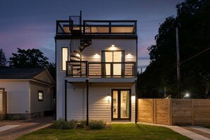 Una casa a due piani con un balcone, una scala a vista e un ingresso ben illuminato.