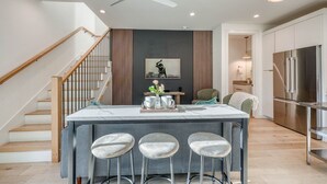 A modern kitchen with a central island, stainless steel appliances, and a staircase leading to another level. - 🎶 East Austin Retreat w/ Balcony + Backyard | Urban Sanctuary | Cloudscape🌮 (Austin)