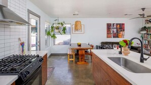A modern kitchen with a central island, a dining area with a wooden table, and a living room with a sofa. - Downtown, UT, Walkable, East Austin Gem (Austin)