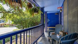 A porch with a blue railing, two Adirondack chairs, a small table, hanging plants, and a door with a red light. - Downtown, UT, Walkable, East Austin Gem (Austin)