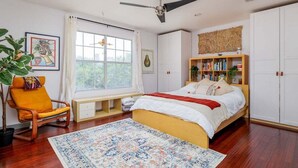 A bedroom with a bed, a window, a ceiling fan, a bookshelf, and a chair. - Downtown, UT, Walkable, East Austin Gem (Austin)