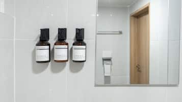 Une salle de bain avec trois bouteilles de produits de la marque « Moment » accrochées au mur et une porte en bois.