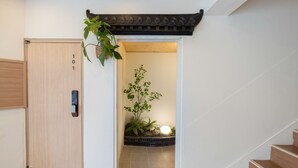 Una puerta de madera con un número, una pequeña planta y un detalle arquitectónico tradicional en la parte superior.