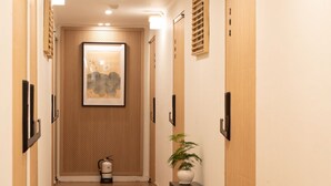 Un pasillo con paneles de madera, una obra enmarcada en la pared, un extintor y una planta en maceta.