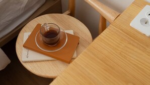 Una pequeña mesa redonda de madera con una taza de té, un cuaderno y un bolígrafo.