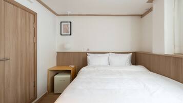 A bedroom with a bed, a nightstand, a bedside table, a framed picture, and a ceiling light.
