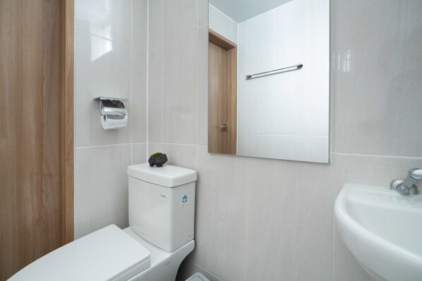 A modern bathroom with a toilet, a sink, and a mirror. - Stay 105 Haenggung Residence (Suwon)