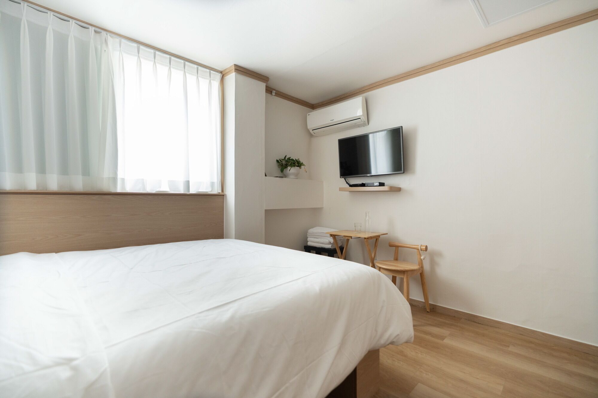 Ein Hotelzimmer mit einem Bett, einem an der Wand montierten Fernseher, einem kleinen Tisch und einem Sessel.