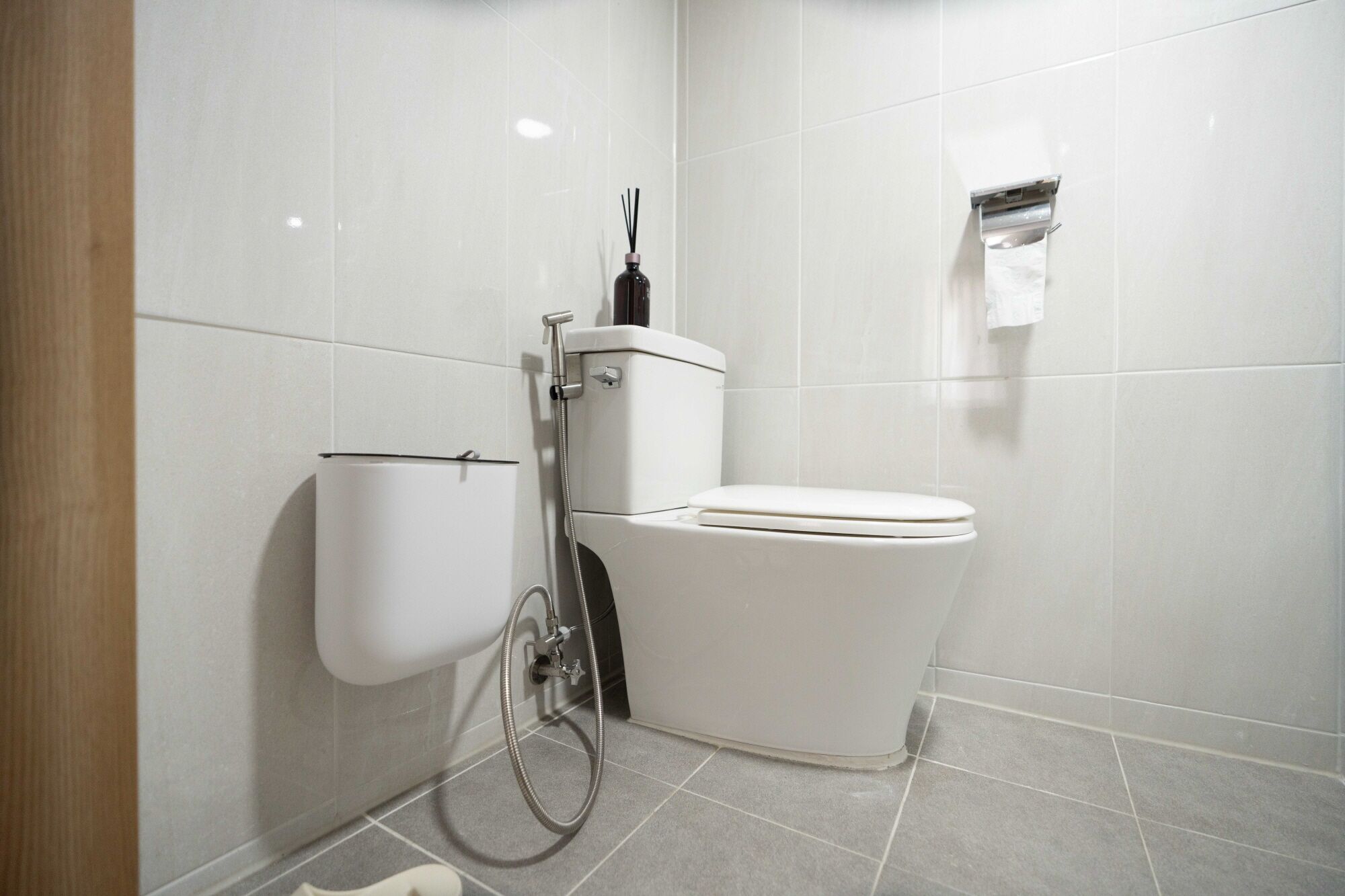 A modern bathroom with a toilet, bidet, and a paper towel dispenser.