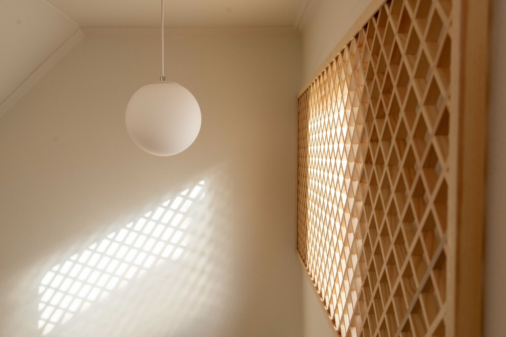 A room with a hanging spherical light fixture and a wooden lattice partition.
