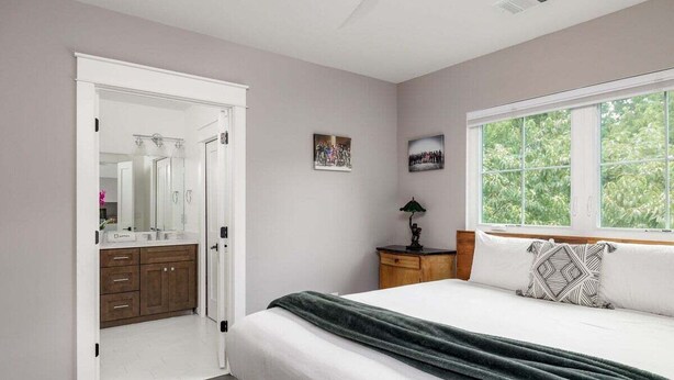 Una camera da letto con un letto, un comodino, una finestra e una porta che conduce al bagno.