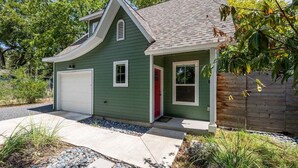 Una casa a un piano con un garage, una porta rossa e un piccolo portico.