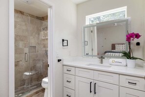 A modern bathroom with a glass-enclosed shower, a white sink, and a large mirror. - Gorgeous Deck, Stunning Views - Treetop Vista (Austin)