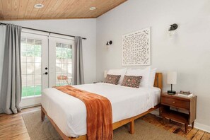 A bedroom with a bed, a nightstand, a wall-mounted light, and a decorative piece. - Walkable, Prime E. Austin Location - Casa Cherico (Austin)