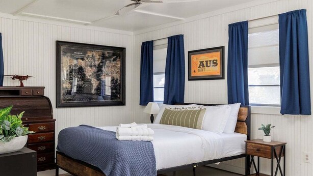 A bedroom with a bed, a nightstand, a dresser, a framed world map, and a framed sign with "AUS" and "Austin TX". - Austin Country Blues Home 3b/2b Close to Town, Zilker Park (Austin)