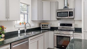 A modern kitchen with white cabinets, a stainless steel range, a microwave, and a toaster oven. - Austin Country Blues Home 3b/2b Close to Town, Zilker Park (Austin)