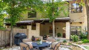 Eine Terrasse im Freien mit Steinboden, einem runden Tisch und vier Stühlen.