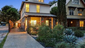 Une maison à deux étages, avec des fondations en pierre, un porche abrité et un jardin bien entretenu.