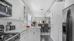 Une cuisine moderne avec des meubles blancs, une cuisinière à gaz, un four à micro-ondes et un réfrigérateur.