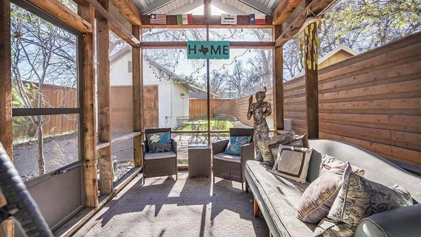 Un espace extérieur aménagé, abrité et doté de mobilier en osier, avec une enseigne portant l’inscription « HOME ».