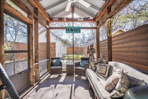 A covered outdoor seating area with wicker furniture and a 'HOME' sign. - 🚶🌮 Walkable Austin Stay with Screened Patio + Workspace | Classically Modern (Austin)