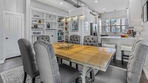 Une cuisine moderne dotée d’un îlot central, d’étagères intégrées et d’un coin repas avec une grande table et des chaises.