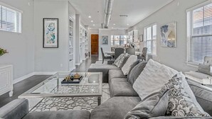 Un salon moderne avec un canapé gris, une table basse en verre et un ventilateur de plafond.