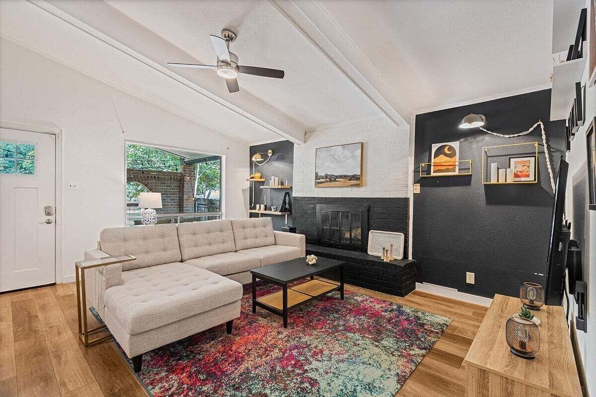 Un salon moderne avec un canapé d’angle, une cheminée et un ventilateur de plafond.