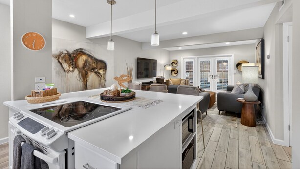 Una cocina moderna con una isla central, luces colgantes y un rincón comedor con sofá y mesa.