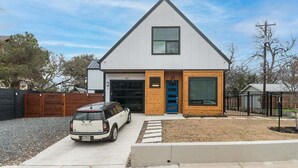 Et moderne hus i et plan med garage, indkørsel og en bil foran.
