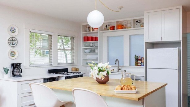 A modern kitchen with a central island, white cabinetry, and a variety of kitchenware. - Free Parking, Walk to Food - Pastel (Austin)