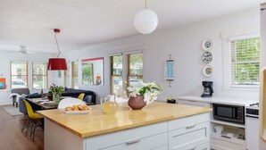 A modern kitchen with a wooden countertop, white cabinets, and a red pendant light. - Free Parking, Walk to Food - Pastel (Austin)