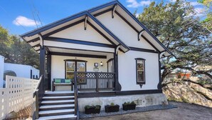 A two-story house with a front porch, steps, and a small garden area. - 🌿 SoCo Retreat by Creek with Workspace | Creekside Bungalow 🎶 (Austin)