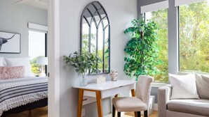 Une chambre moderne avec un lit, un bureau, une chaise et une grande fenêtre donnant sur des arbres.