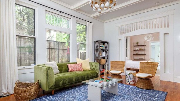 A living room with a green sofa, wicker chairs, a coffee table, and a patterned rug. - Free Parking, Walk to Zilker, 3BR - Austin Craftsman (Austin)