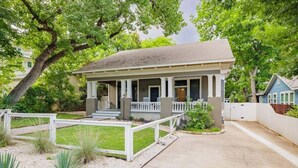 A two-story house with a covered porch, a front yard with a white fence, and a driveway. - Free Parking, Walk to Zilker, 3BR - Austin Craftsman (Austin)