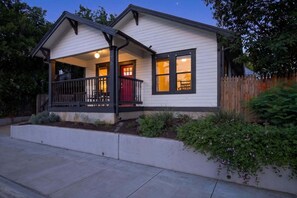 A single-story house with a porch, a red door, and a small garden area. - 🔥 Urban Charm · East Austin · Walk to BBQ · Fire Pit & EV Charger ⚡ (Austin)